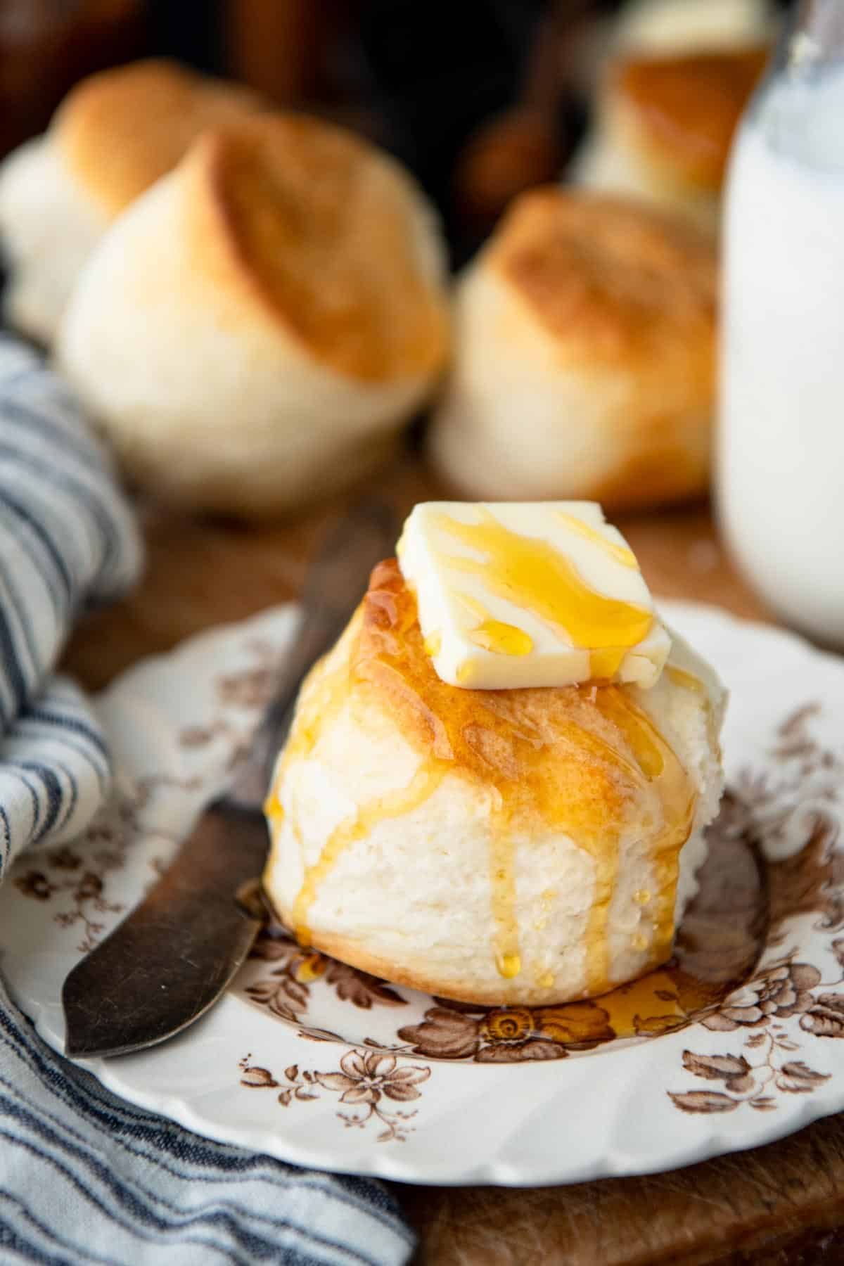 Whipped cream biscuits on a plate with butter and honey.
