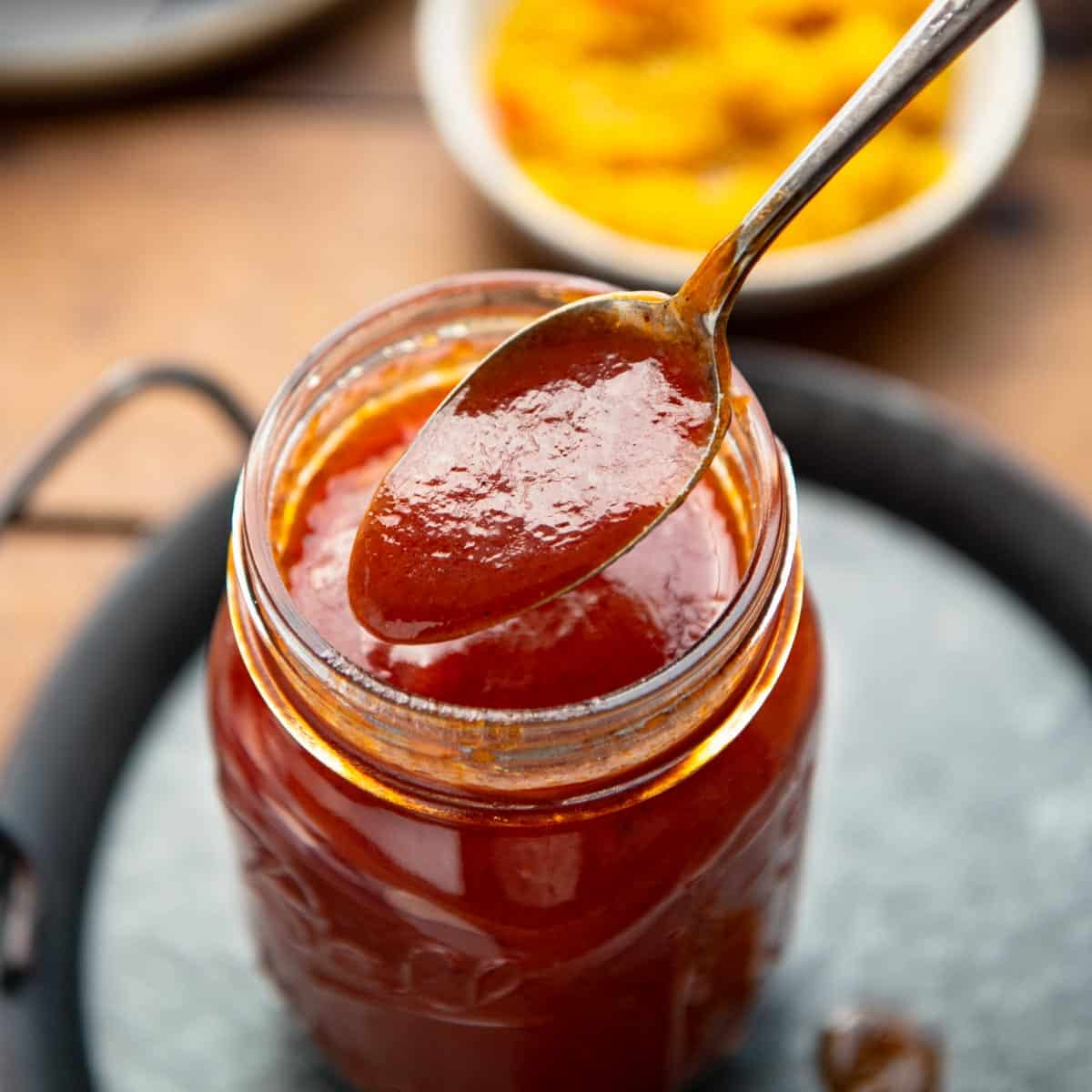 Spoon in a jar of homemade maple bbq sauce.