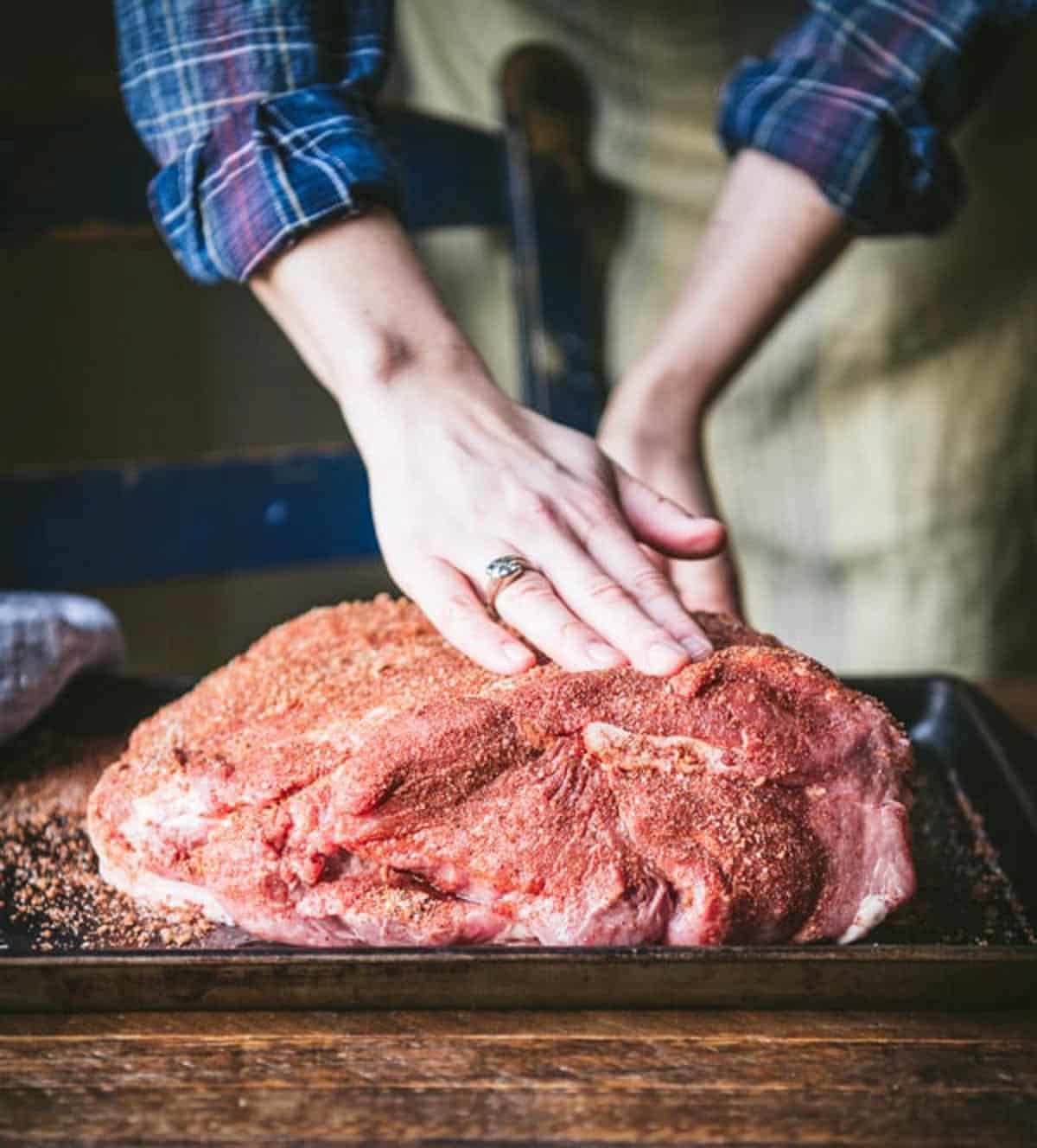 Seasoning pork shoulder with a bbq dry rub.