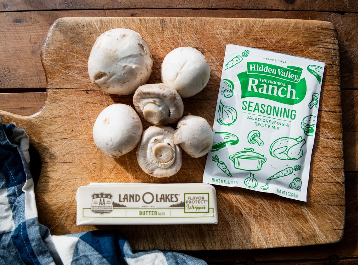 Ingredients for crockpot mushrooms on a wooden cutting board.