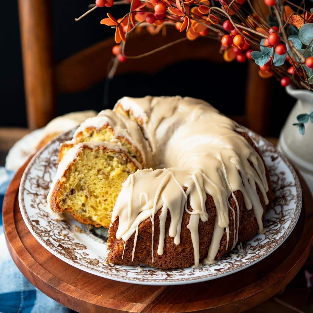 Square side shot of a maple walnut cake on a wooden cake stand.