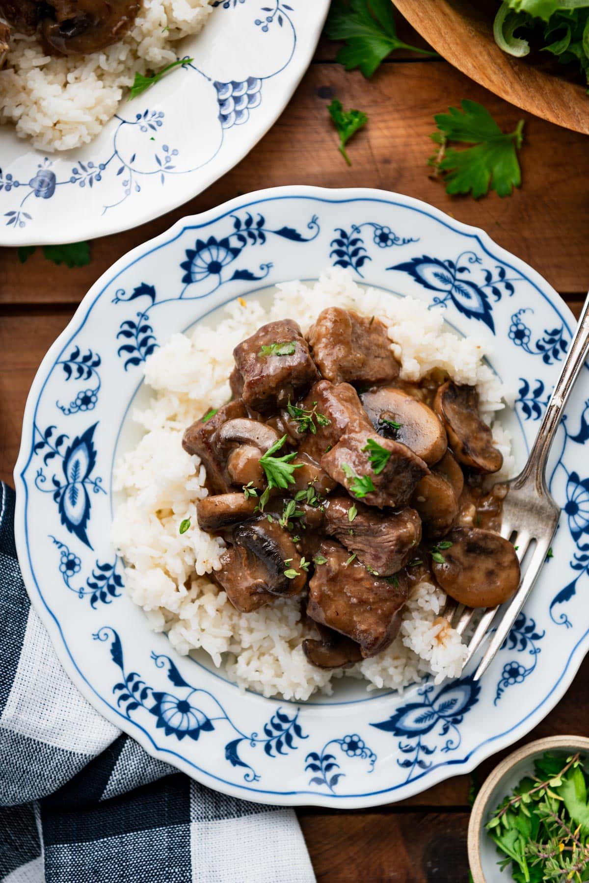 Close overhead shot of a bowl of beef tips and rice on a table.