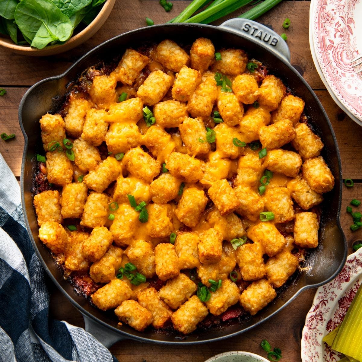 Square overhead shot of cheeseburger tater tot casserole in a cast iron skillet on a wooden table.