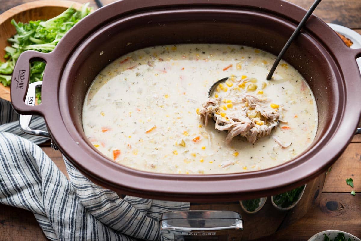 Ladle in a slow cooker full of chicken corn soup.