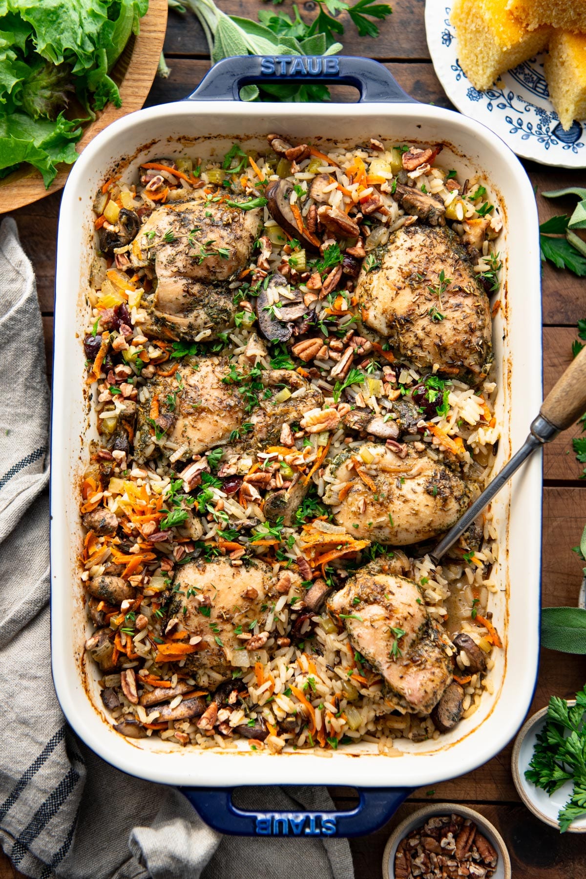 Overhead shot of dump-and-bake chicken and wild rice pilaf in a dish on top of a wooden dinner table.