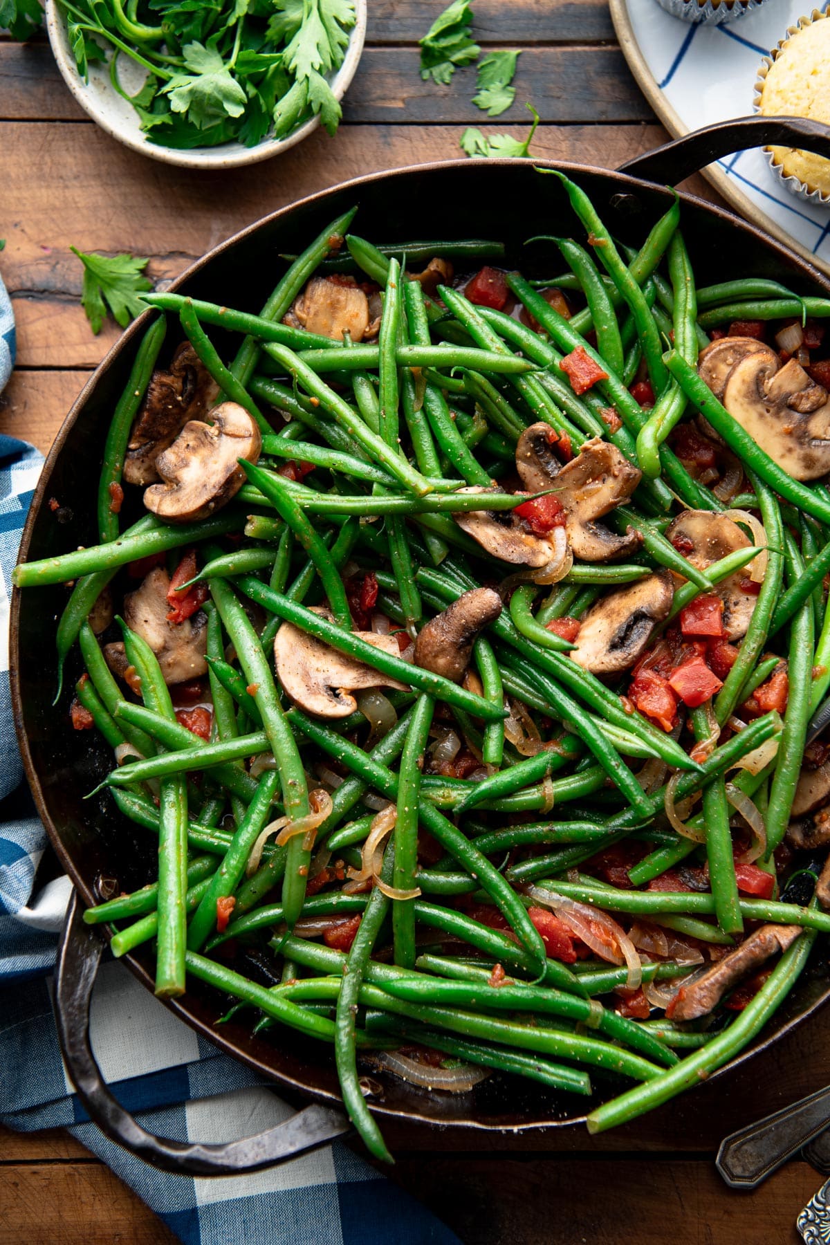 Overhead image of green beans with mushrooms in a cast iron pan.