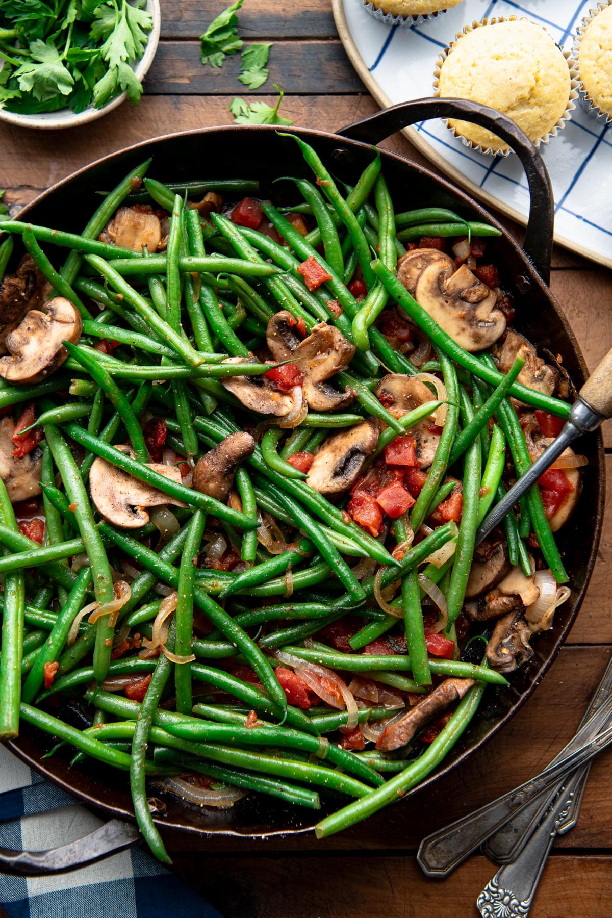 Close overhead shot of green beans with mushrooms and onions in a pan.