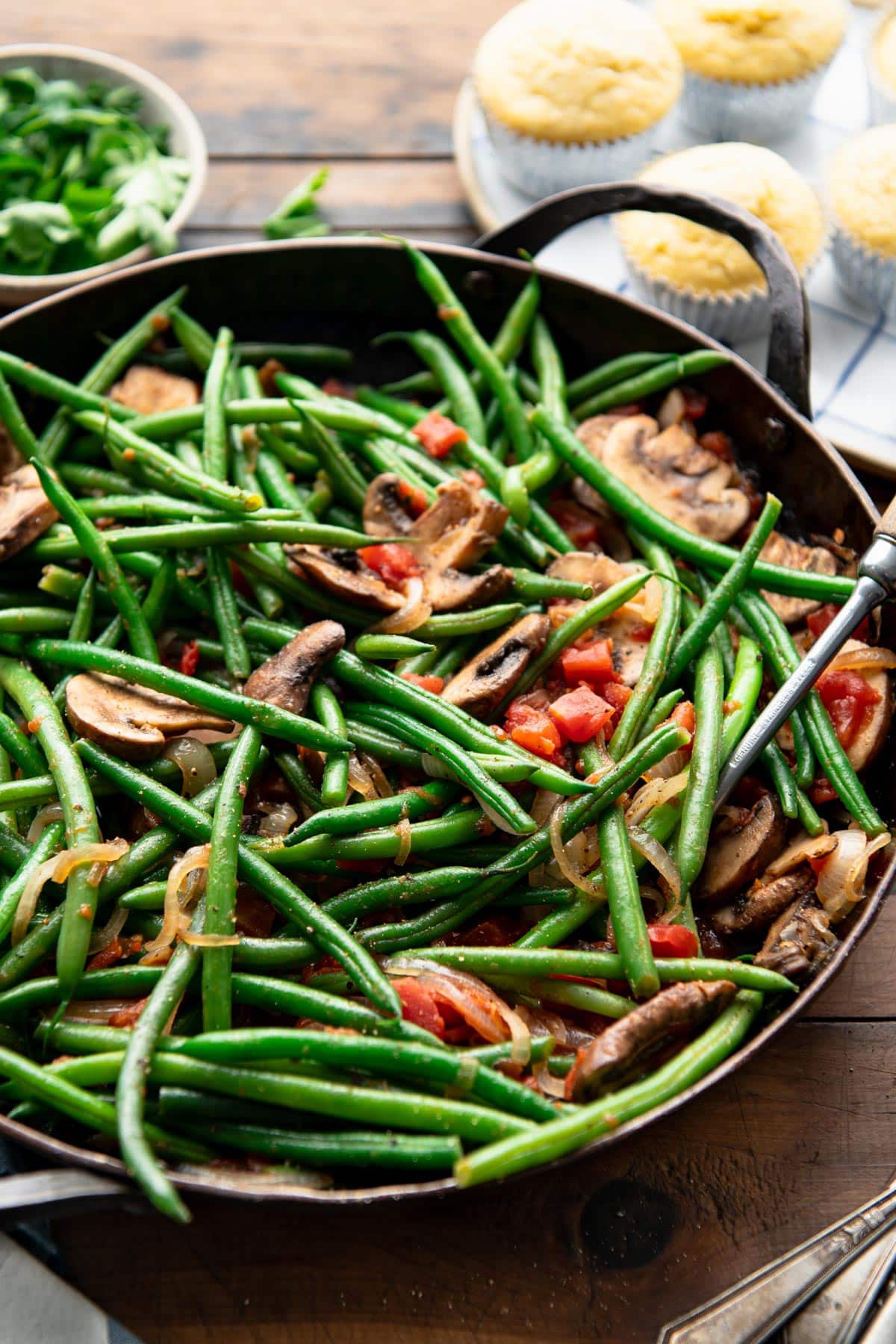 Close up side dish of a skillet of green beans and mushrooms.