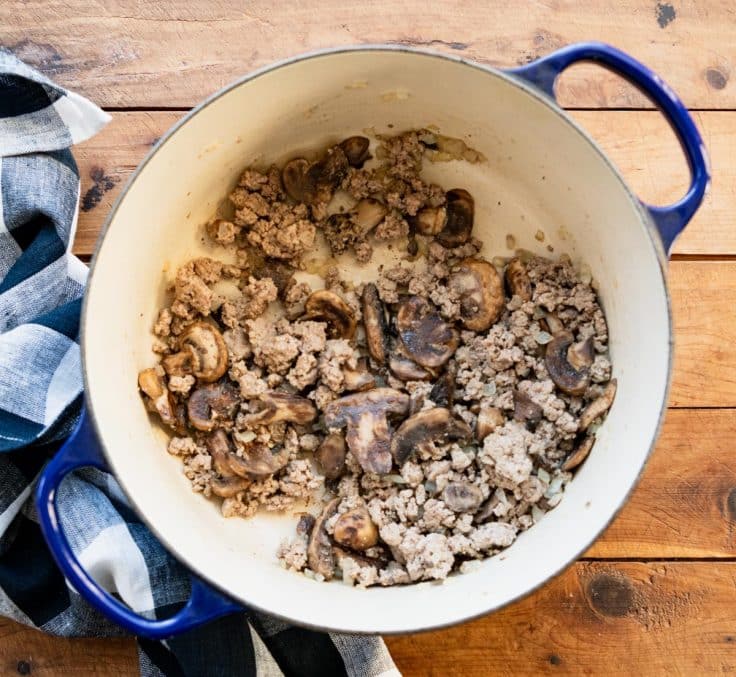 Browning ground beef with mushrooms and onions in a Dutch oven.