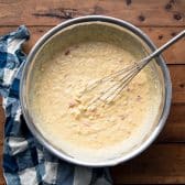 Whisking together Jiffy corn bread batter with creamed corn and cheese.