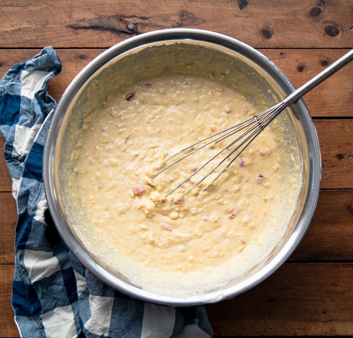 Whisking together Jiffy corn bread batter with creamed corn and cheese.