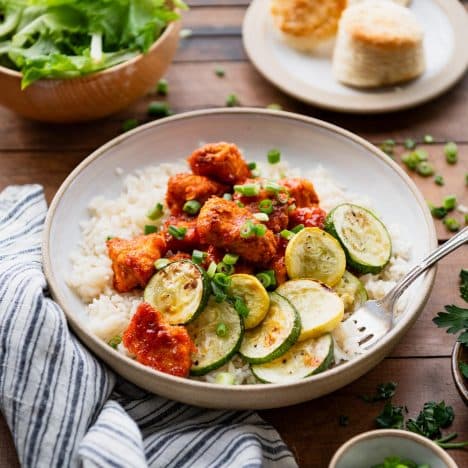 Square side shot of sheet pan orange marmalade chicken with rice and zucchini in a bowl.