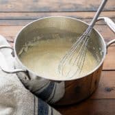 Whisking cheese grits in a pot.