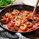Horizontal image of a pan of shrimp in tomato gravy.