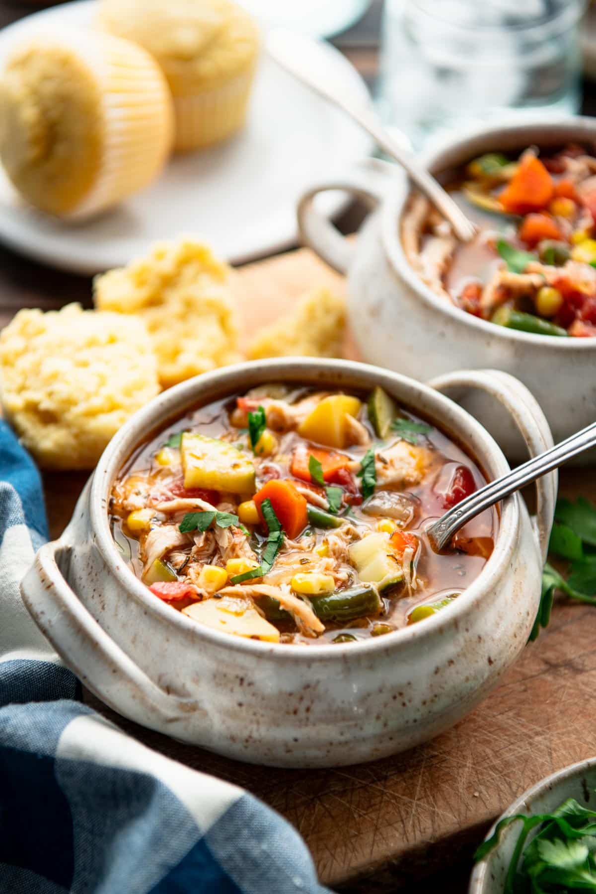 Two bowls of easy turkey vegetable soup on a table with cornbread.