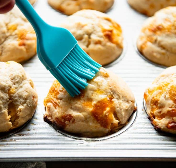 Brushing bisquick biscuits with melted butter.