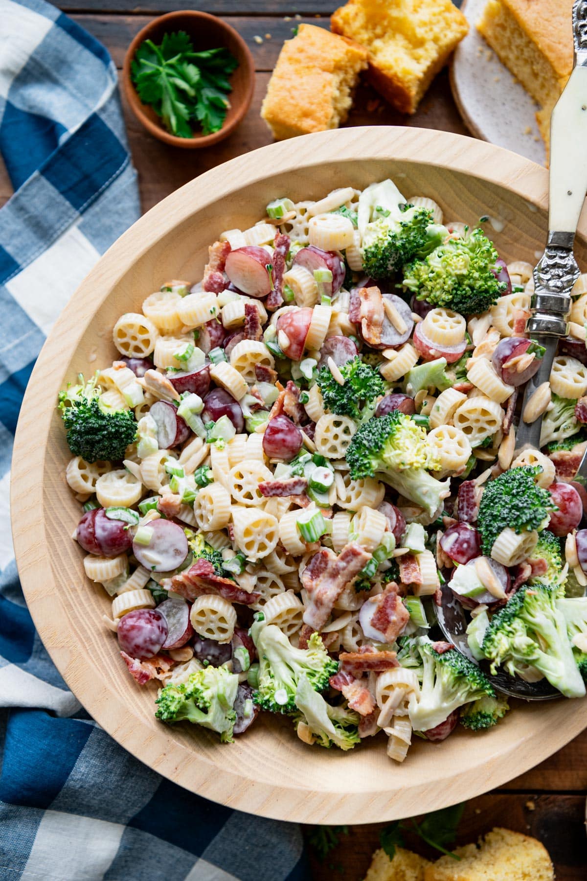 Close overhead image of a wooden bowl full of broccoli and grape salad.