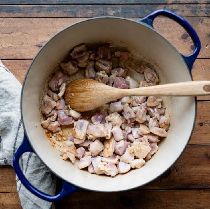 Browning diced chicken in a Dutch oven.