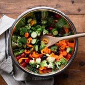 Stirring together raw vegetables in a mixing bowl.