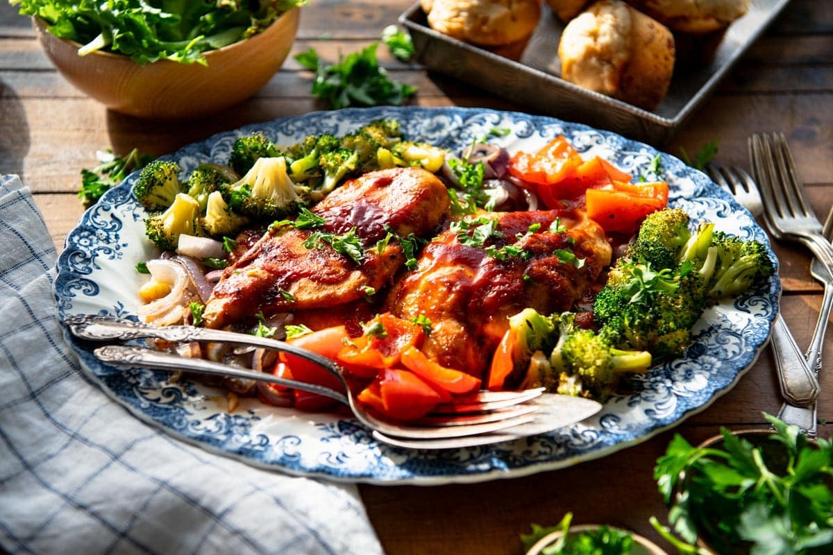 Horizontal image of a platter of bbq chicken and roasted vegetables.