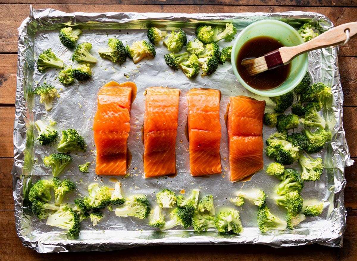 Process shot showing how to make baked honey glazed salmon recipe with broccoli on a sheet pan.