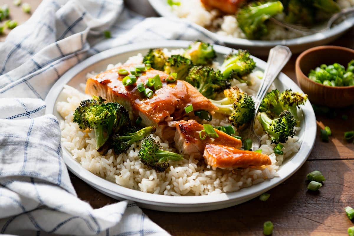 Horizontal side shot of sheet pan salmon with broccoli on a table.