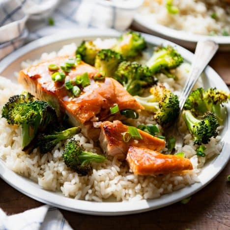 Square side shot of the best baked honey glazed salmon recipe on a white plate with rice and broccoli.