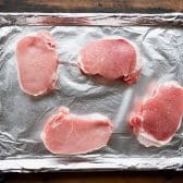 Thick cut pork chops on a baking sheet before the oven.