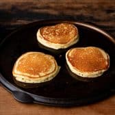 Jiffy cornmeal pancakes cooking on a cast iron griddle.
