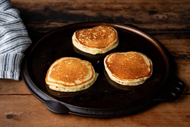 Jiffy cornmeal pancakes cooking on a cast iron griddle.