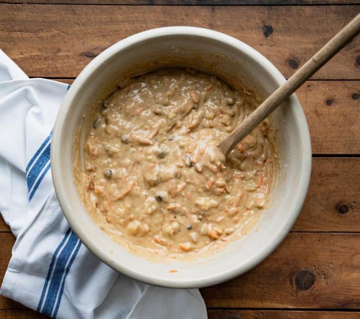 Overhead shot of a wooden spoon in a bowl of carrot bread batter.