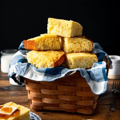 Square side shot of cornbread with corn in a basket.