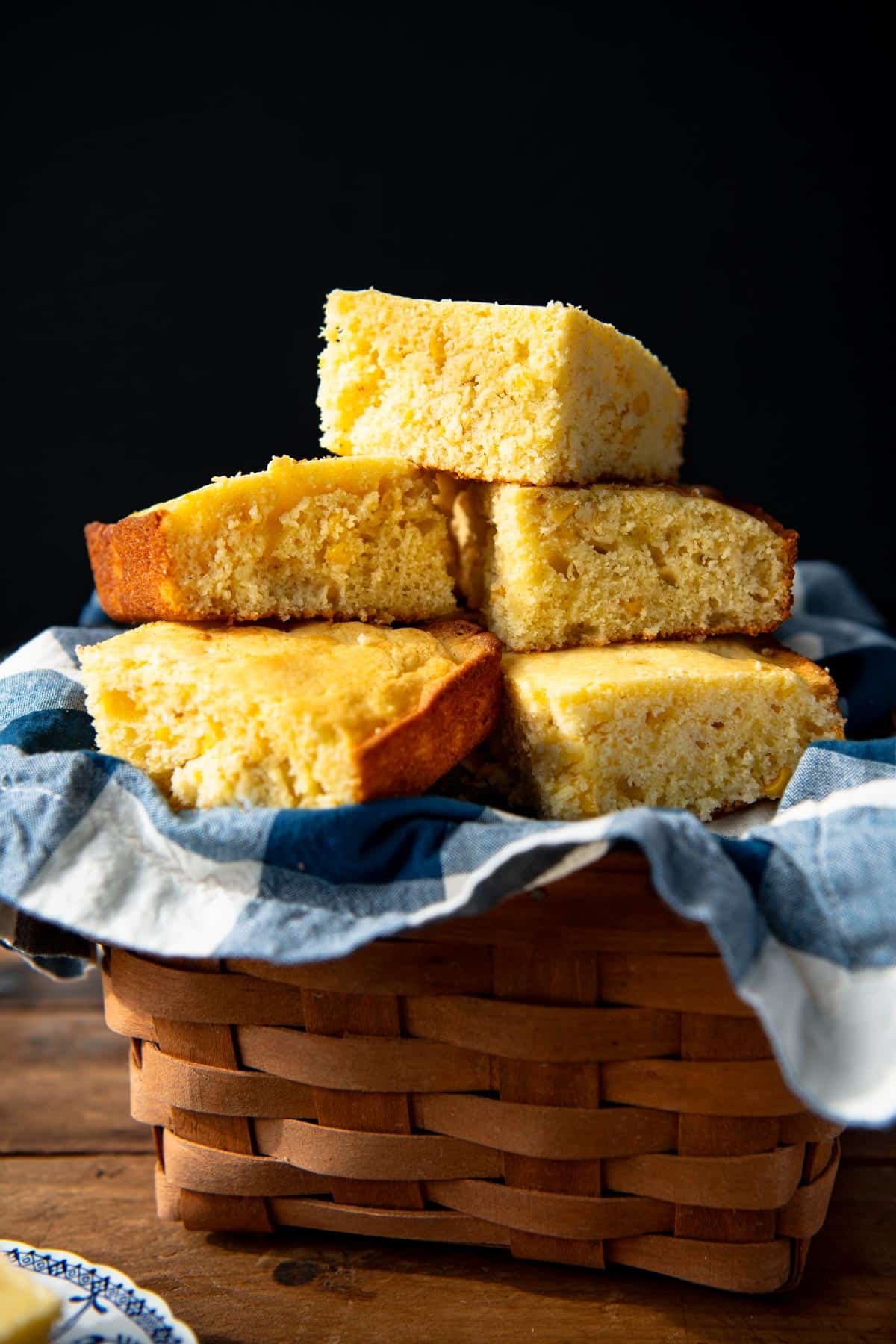 Close up side shot of cornbread with corn in a basket.