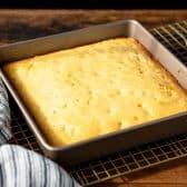 Horizontal side shot of cornbread with corn in a square baking dish.