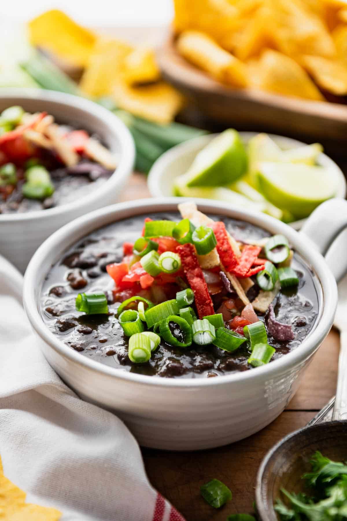 Side shot of two bowls of easy black bean soup on a table.