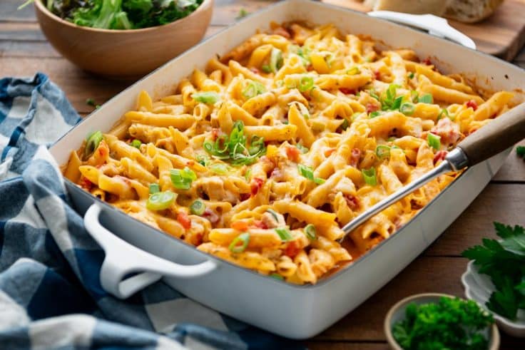 Horizontal side shot of a white baking dish full of buffalo chicken pasta.