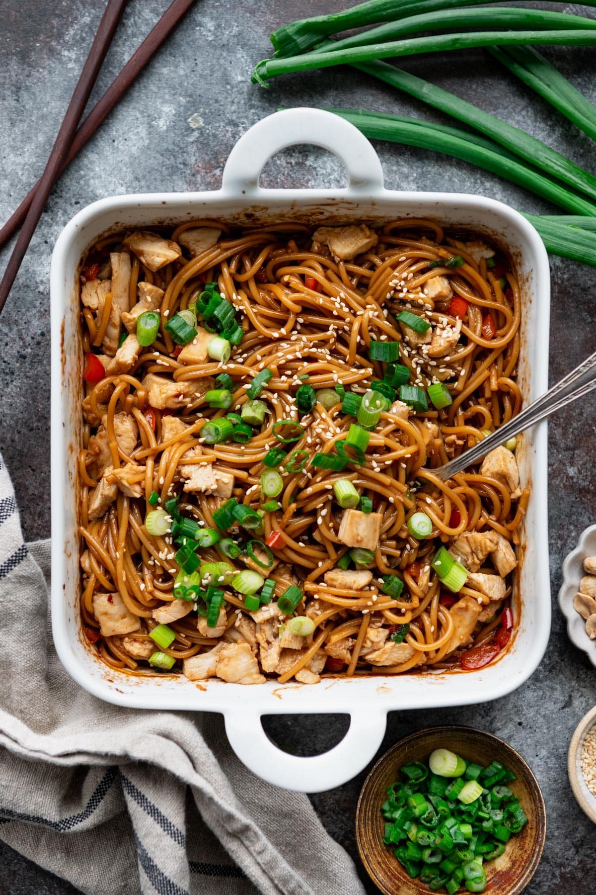 Baked sesame noodles with chicken in a white dish.