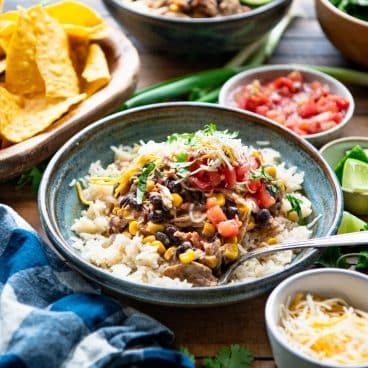 Square side shot of fiesta crockpot chicken on a bowl of rice.