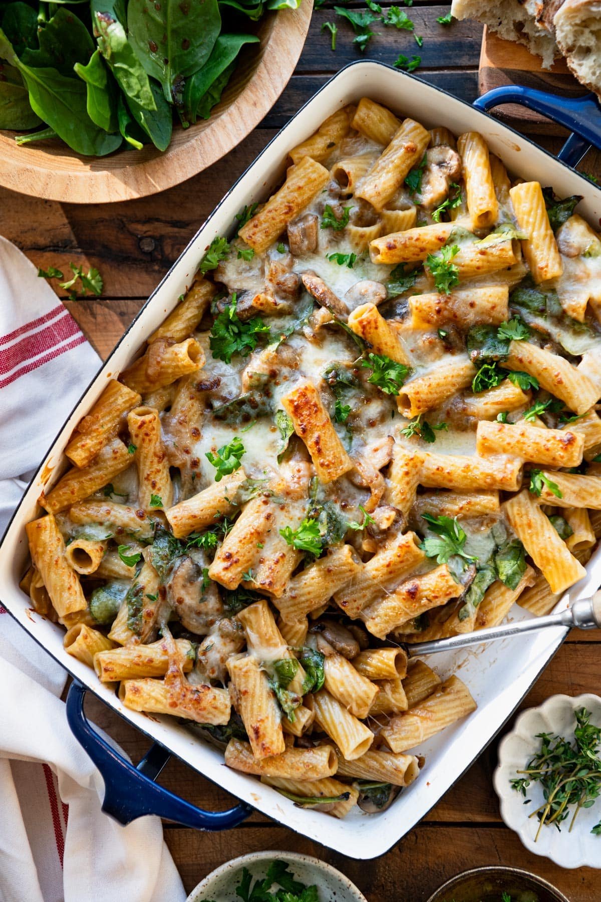 French onion pasta bake on a table with a side salad and bread.