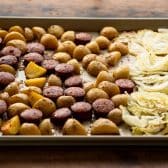 Sausage cabbage and potatoes on a baking sheet.