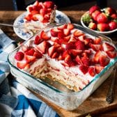Square side shot of a strawberry cream cheese icebox cake in a glass dish on a table.