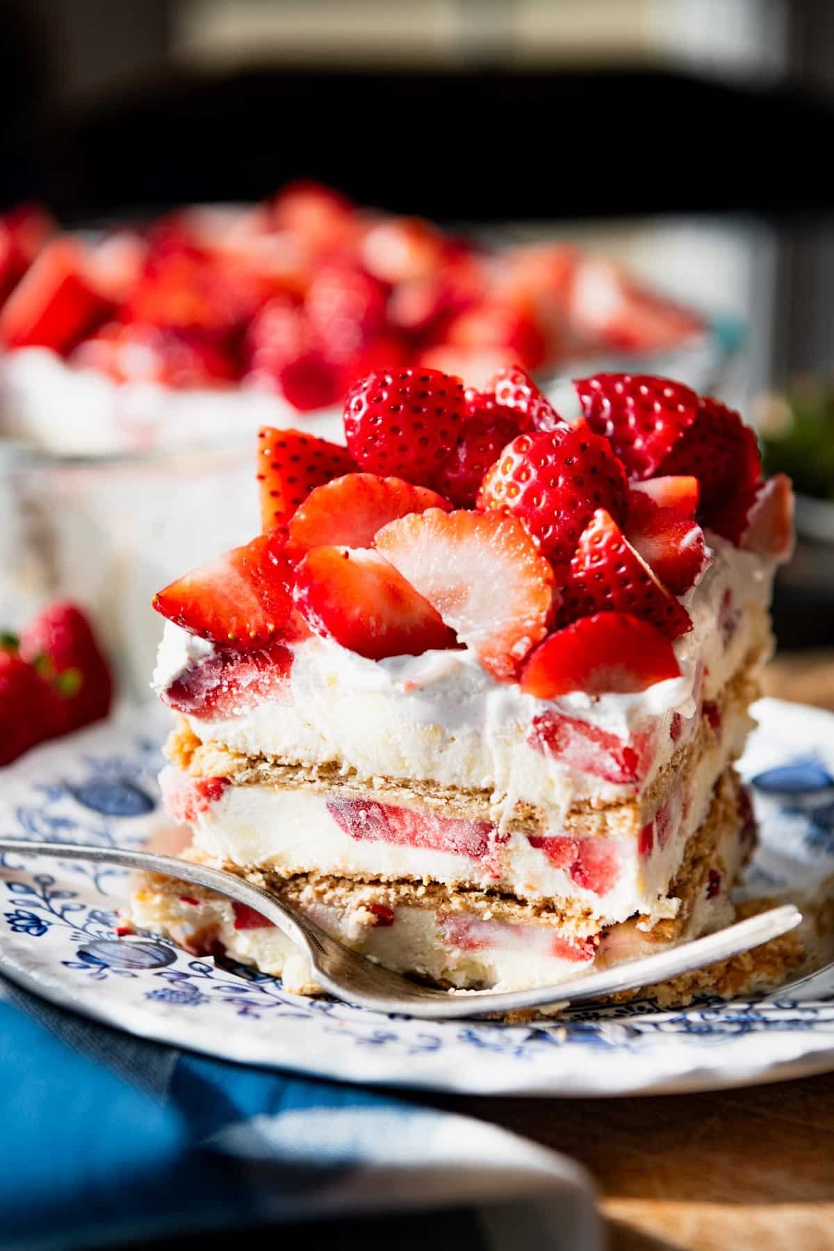 Close up side shot of a slice of strawberry cream cheese icebox cake on a plate.