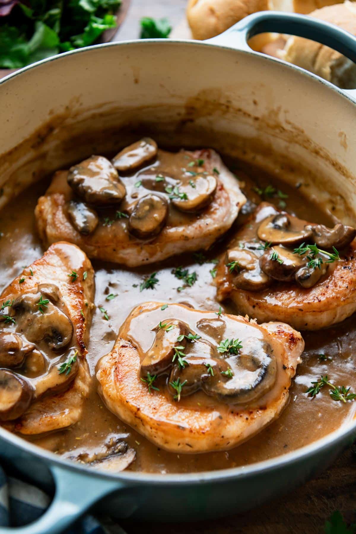 Pork chops and mushroom gravy in a large cast iron Dutch oven.