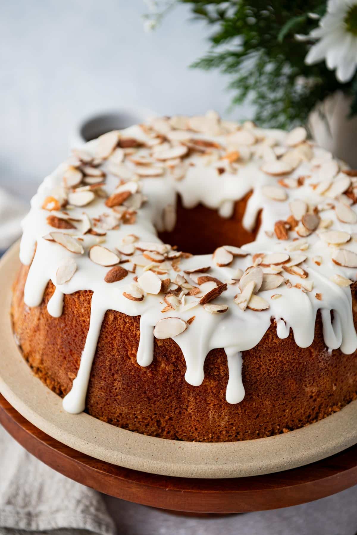 Easy almond pound cake on a plate with almond glaze and toasted almonds on top.