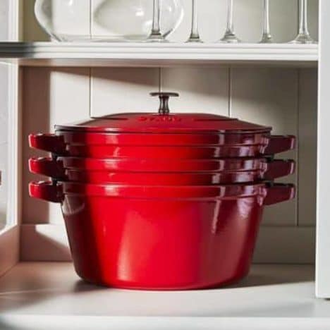 Square side shot of a red stackable cast iron cookware set.