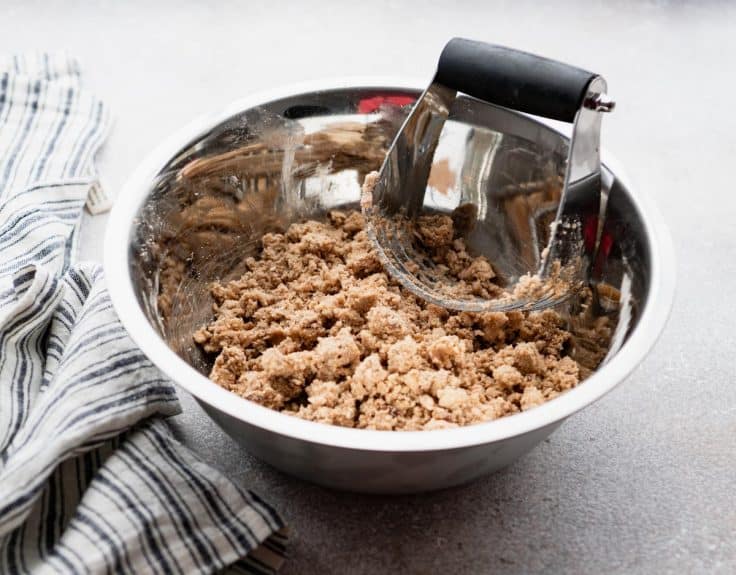 Pastry cutter in a bowl of streusel.