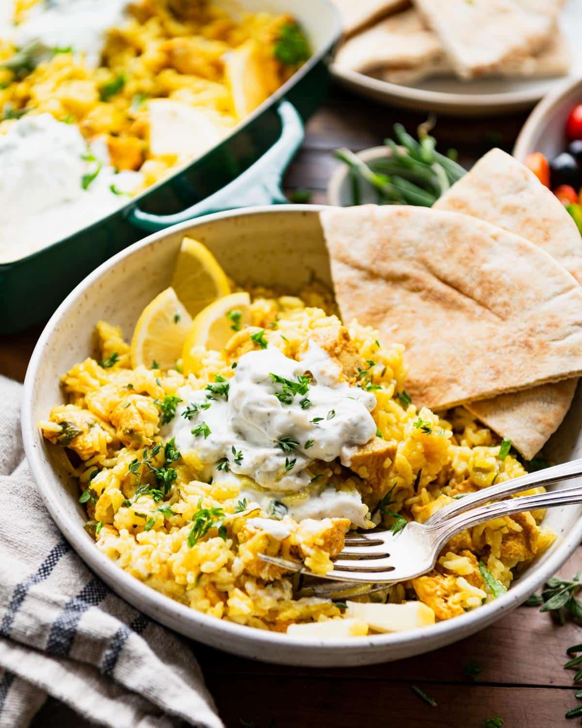 Side shot of a bowl of chicken tzatziki casserole with a side of pita.