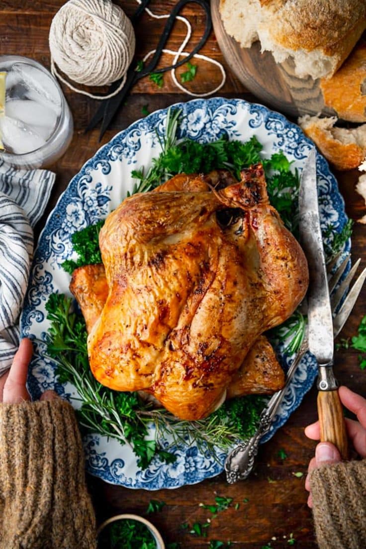 A crisp and juicy whole roasted dutch oven chicken on a blue and white tray.