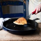 Pan frying chicken cutlets in a cast iron skillet.