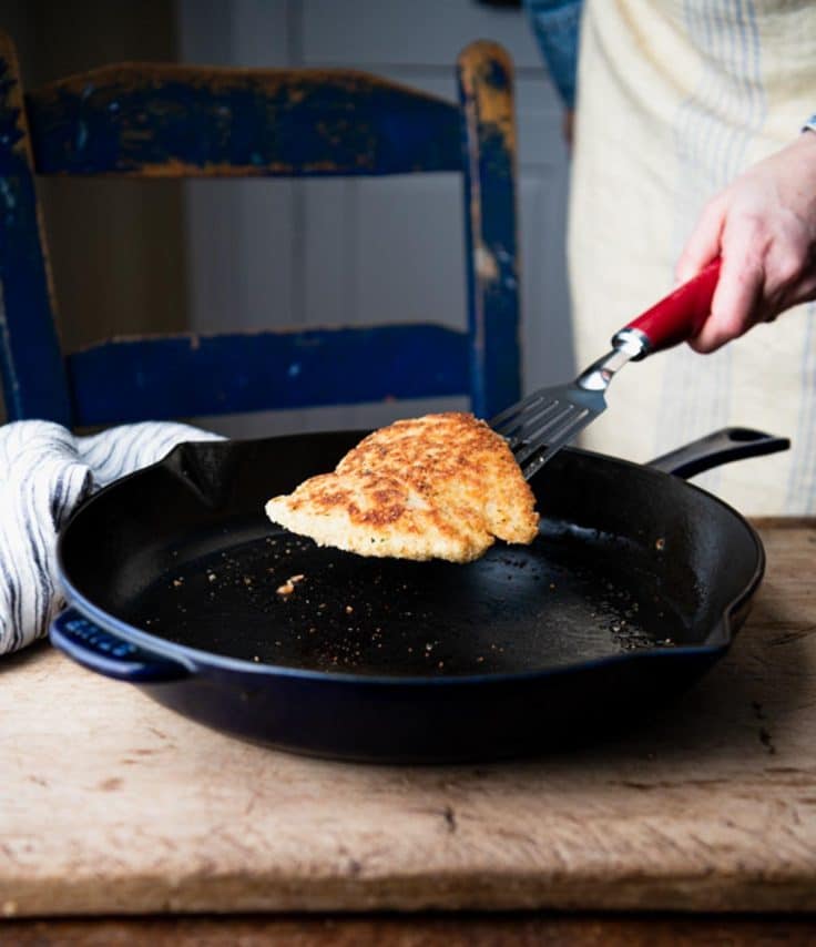 Pan frying chicken cutlets in a cast iron skillet.